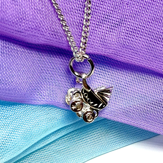A silver-toned metal snowmobile pendant necklace on a matching chain, displayed against a draped purple and light blue mesh fabric background.