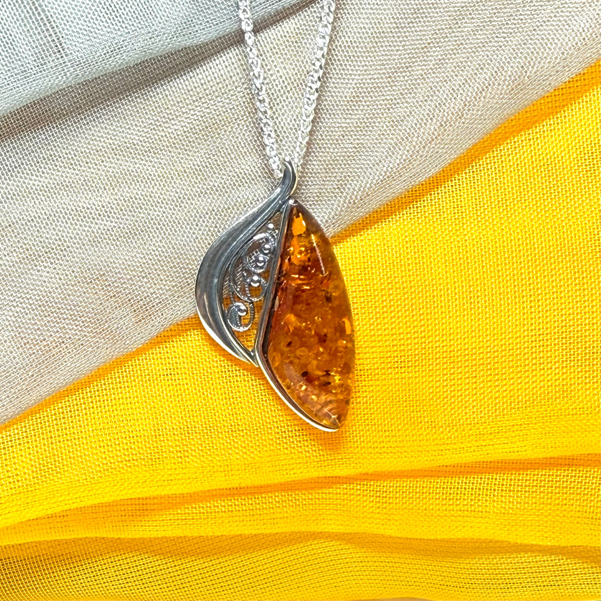 A Sterling silver real amber irregular marquise shaped necklace swirled open pendant
