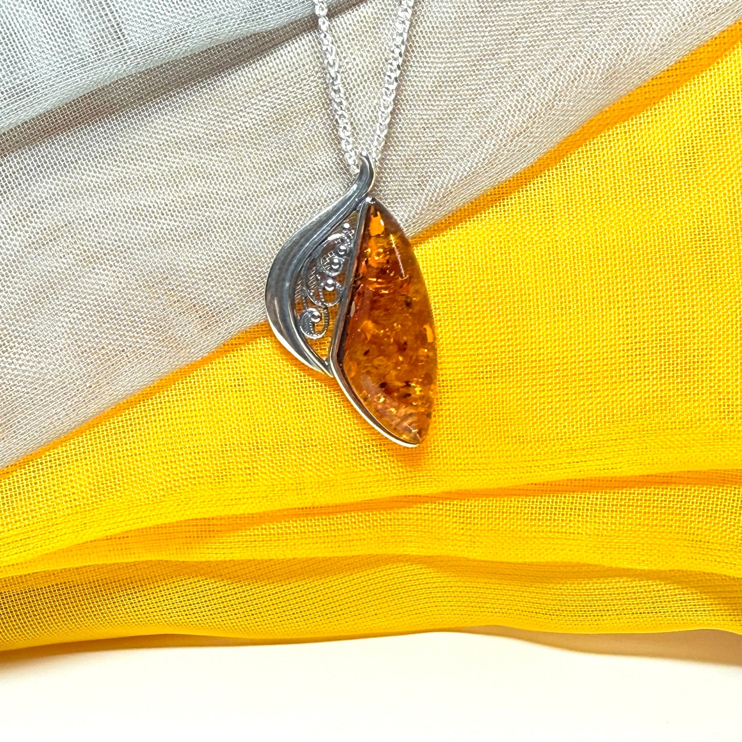 A Sterling silver real amber irregular marquise shaped necklace swirled open pendant