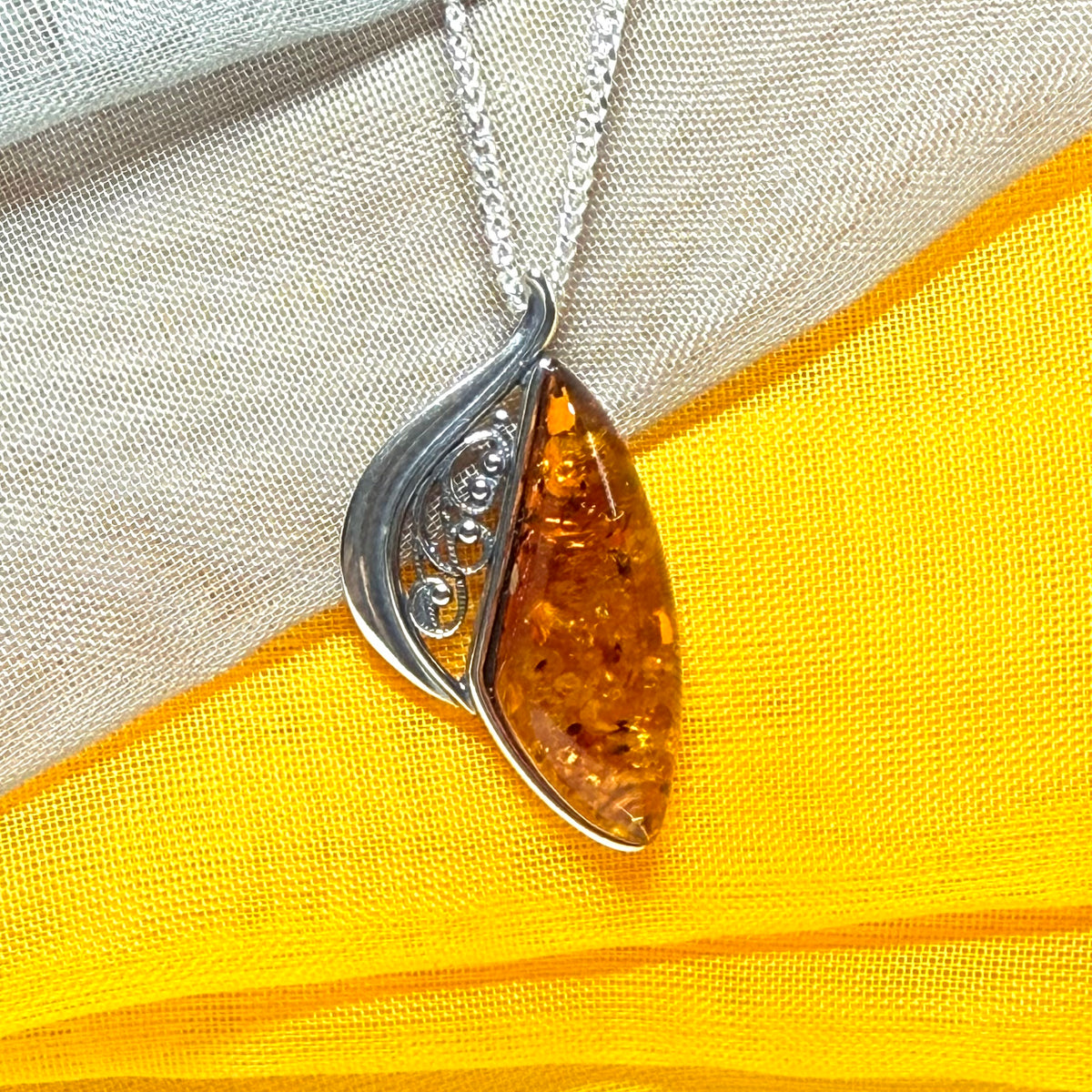 A Sterling silver real amber irregular marquise shaped necklace swirled open pendant