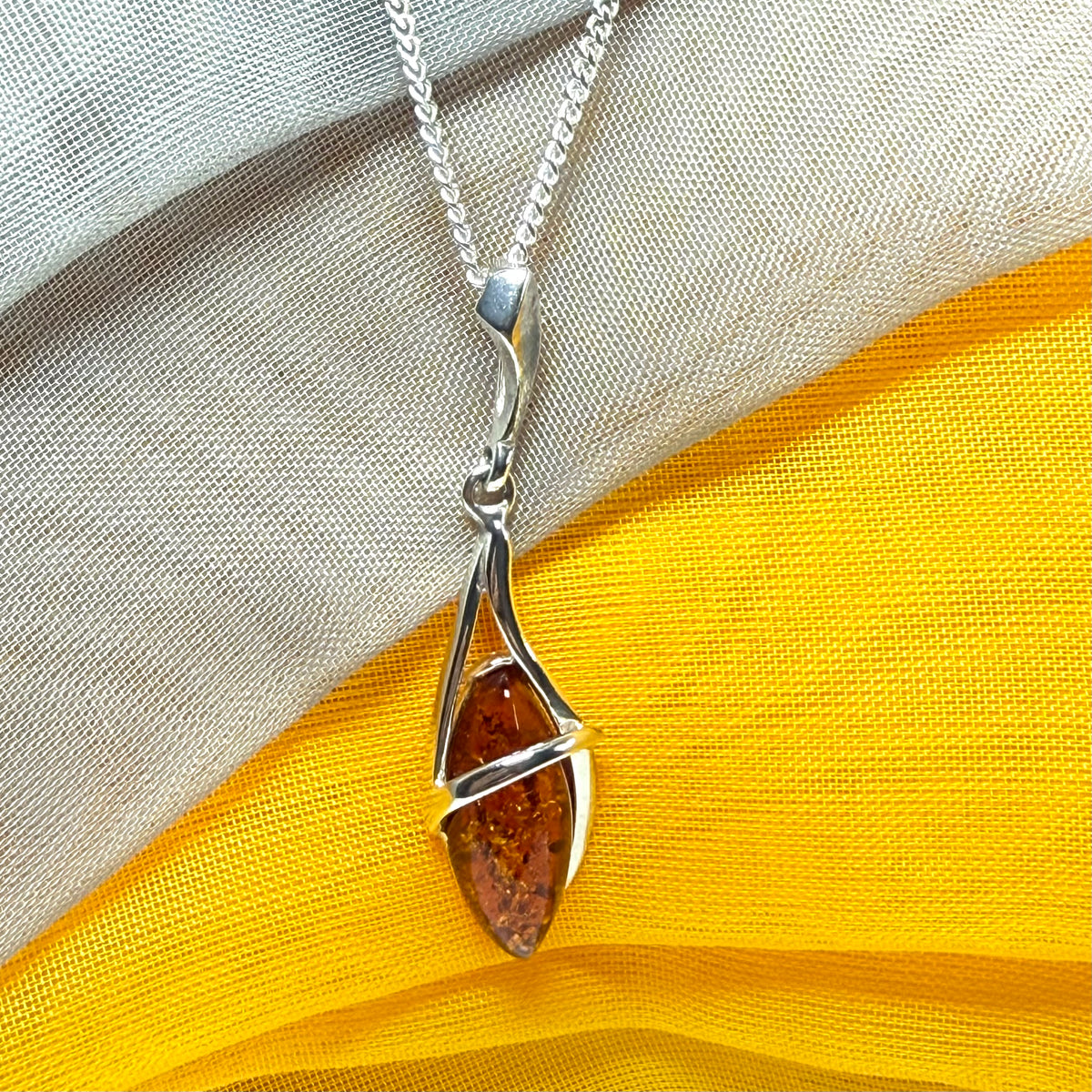 A Sterling silver real amber marquise shaped necklace swirled open pendant with chain