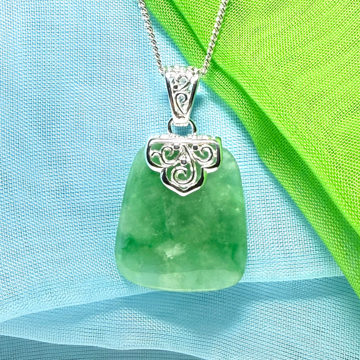 A green real jade necklace with a large shaped and patterned pendant with chain