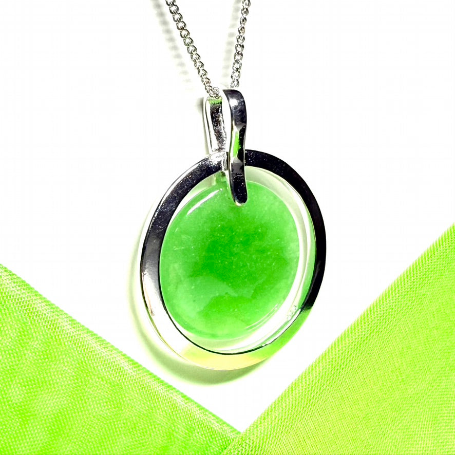 A large sterling silver round shaped green real jade necklace halo styled pendant with a chain included with it