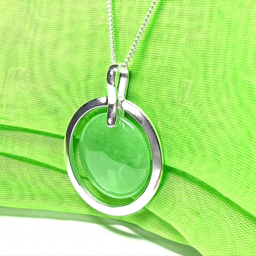 A large sterling silver round shaped green real jade necklace halo styled pendant with a chain included with it
