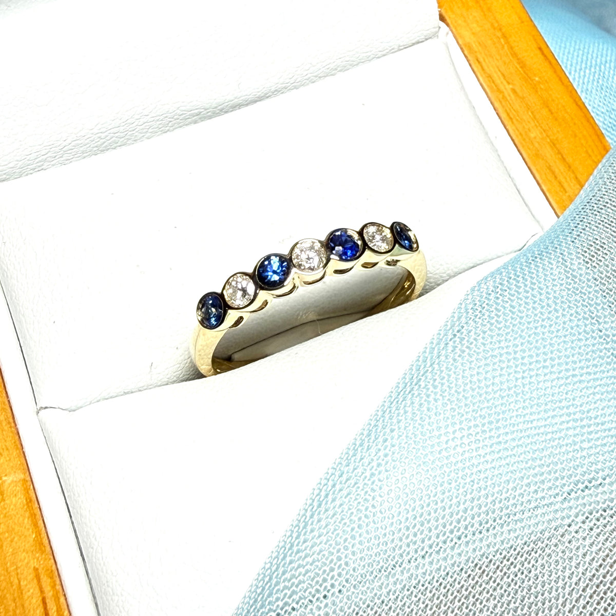 A real blue sapphire and diamond yellow gold eternity ring smooth setting