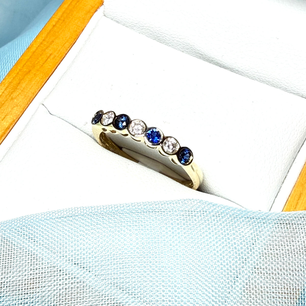 A real blue sapphire and diamond yellow gold eternity ring smooth setting