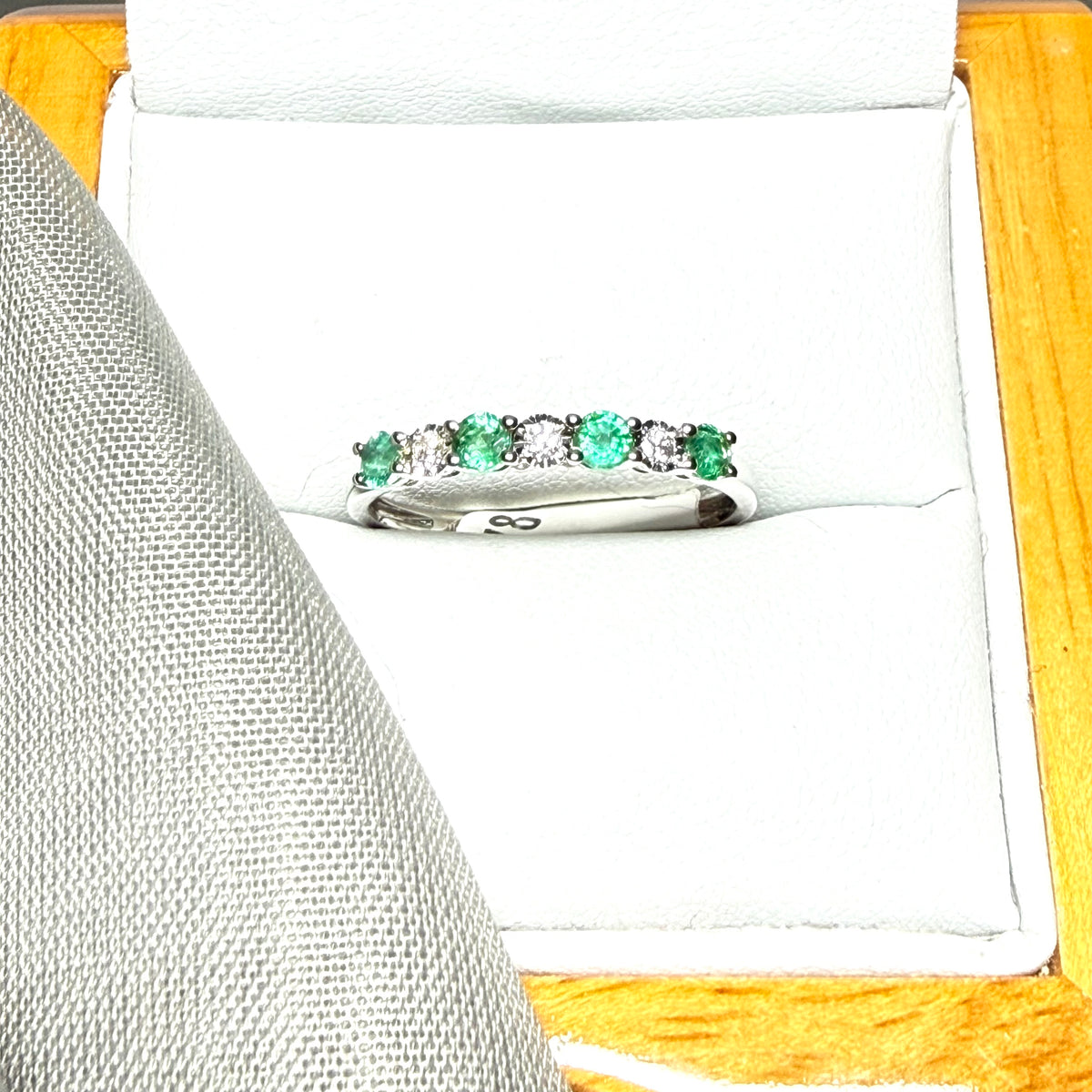 A real emerald and diamond white gold eternity ring claw setting