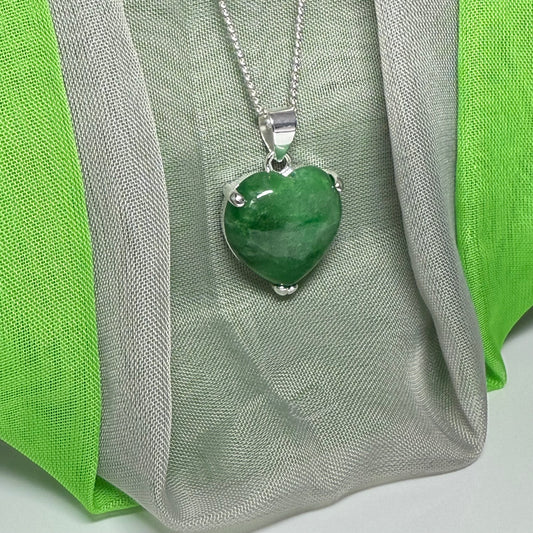 Green heart-shaped pendant on a silver chain against a green and gray fabric background