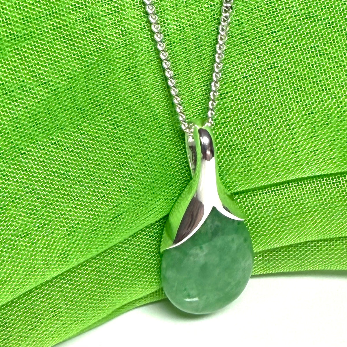 A real green jade necklace in a teardrop or pear shaped including a solid chain