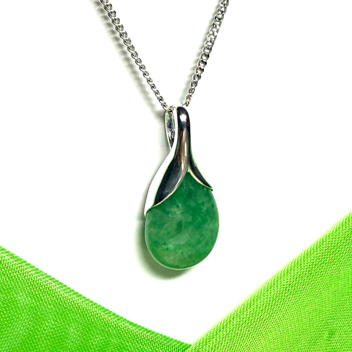 A real green jade necklace in a teardrop or pear shaped including a solid chain
