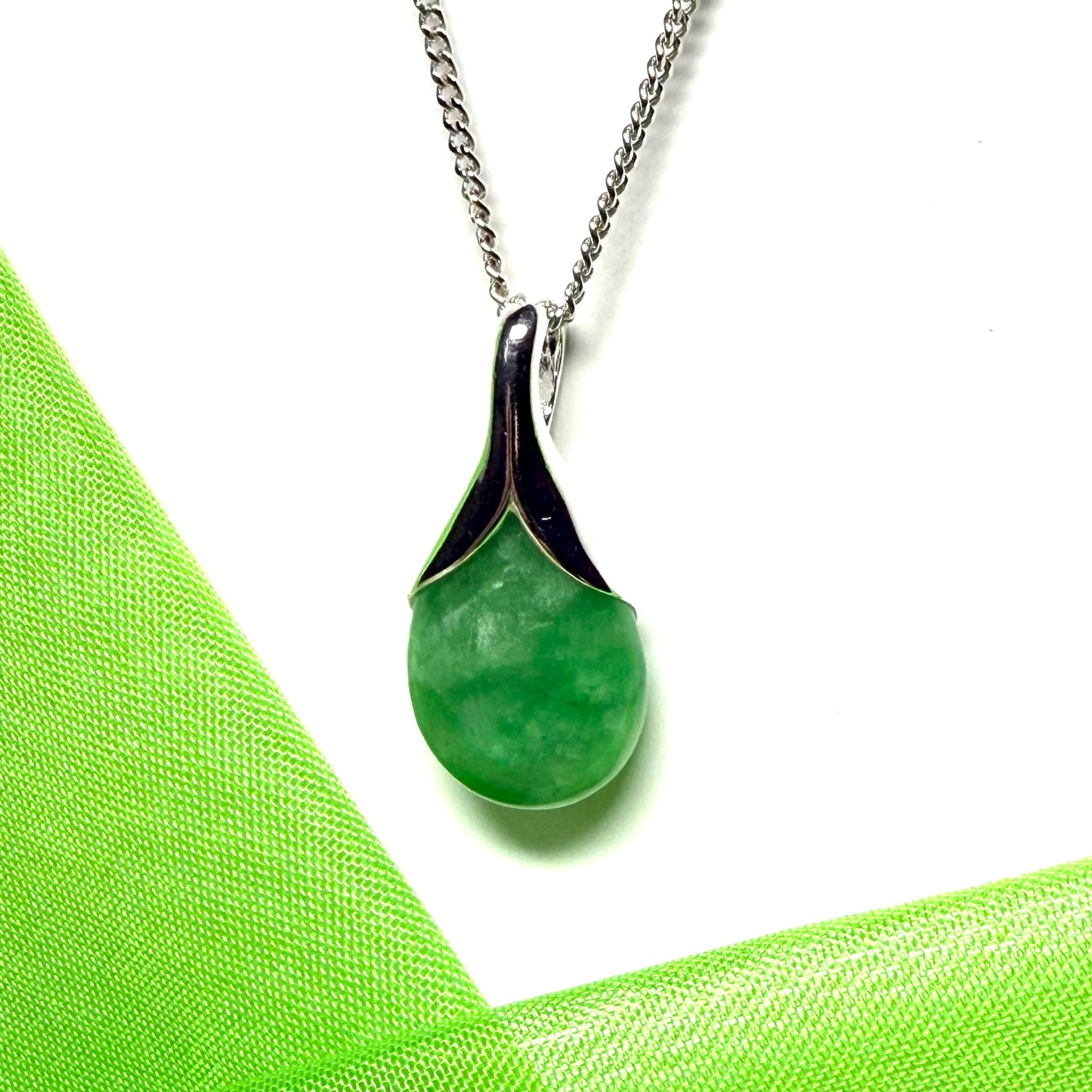 A real green jade necklace in a teardrop or a pear shape including a solid curb chain
