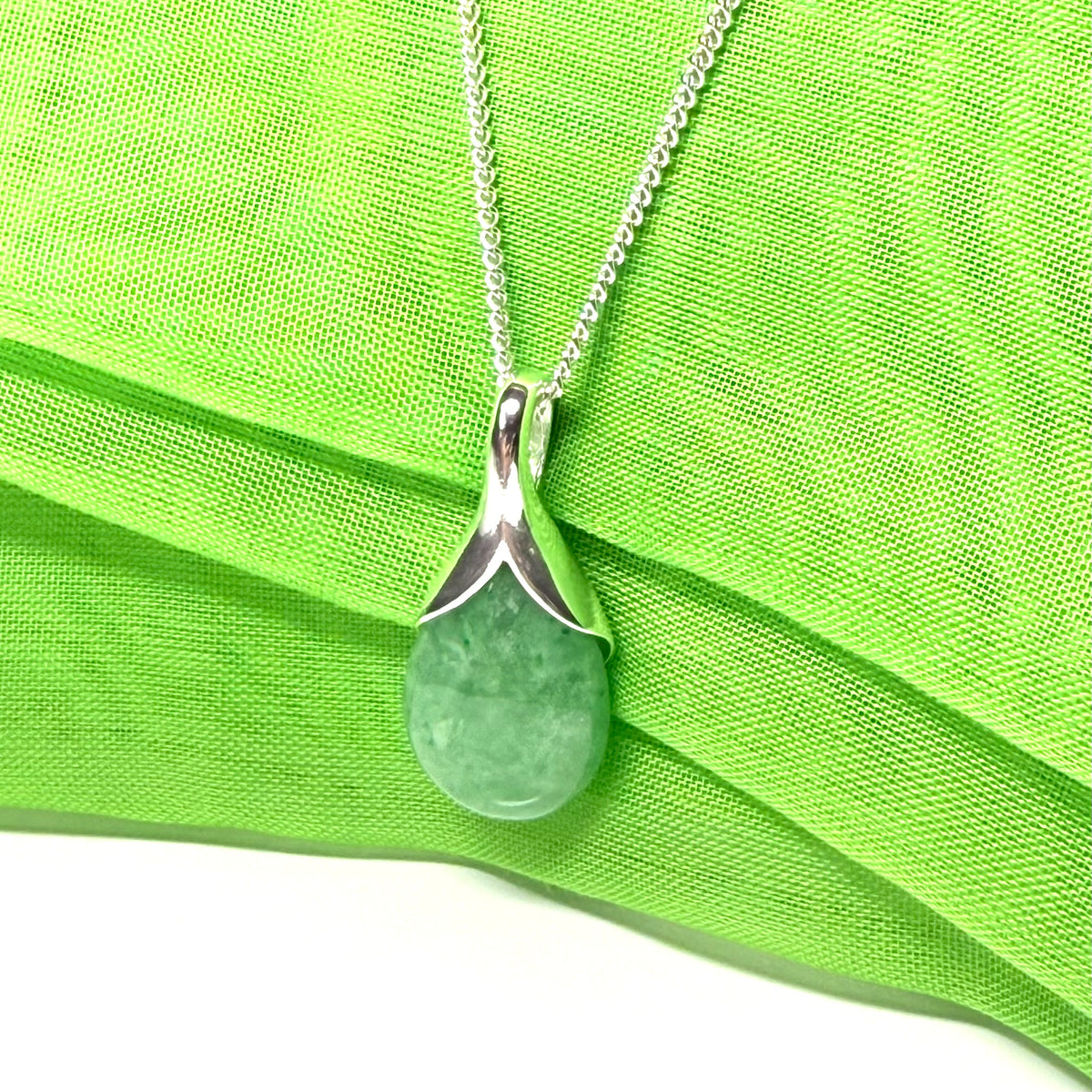 A real green jade necklace in a teardrop or pear shaped including a solid chain