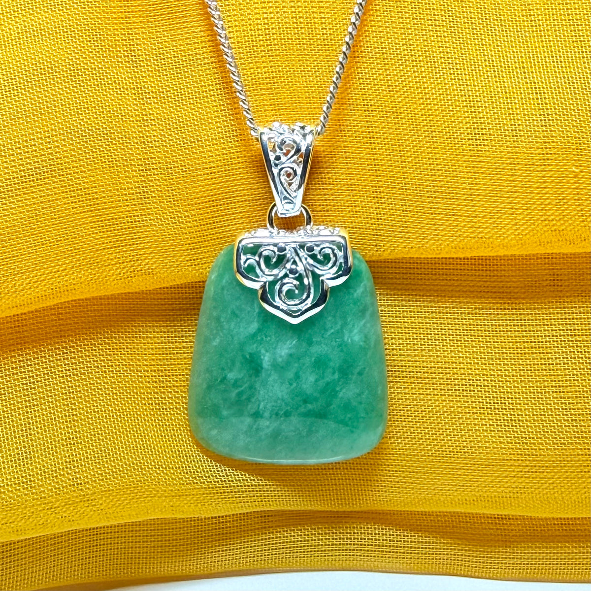 A real green jade necklace with a large shaped and patterned top pendant