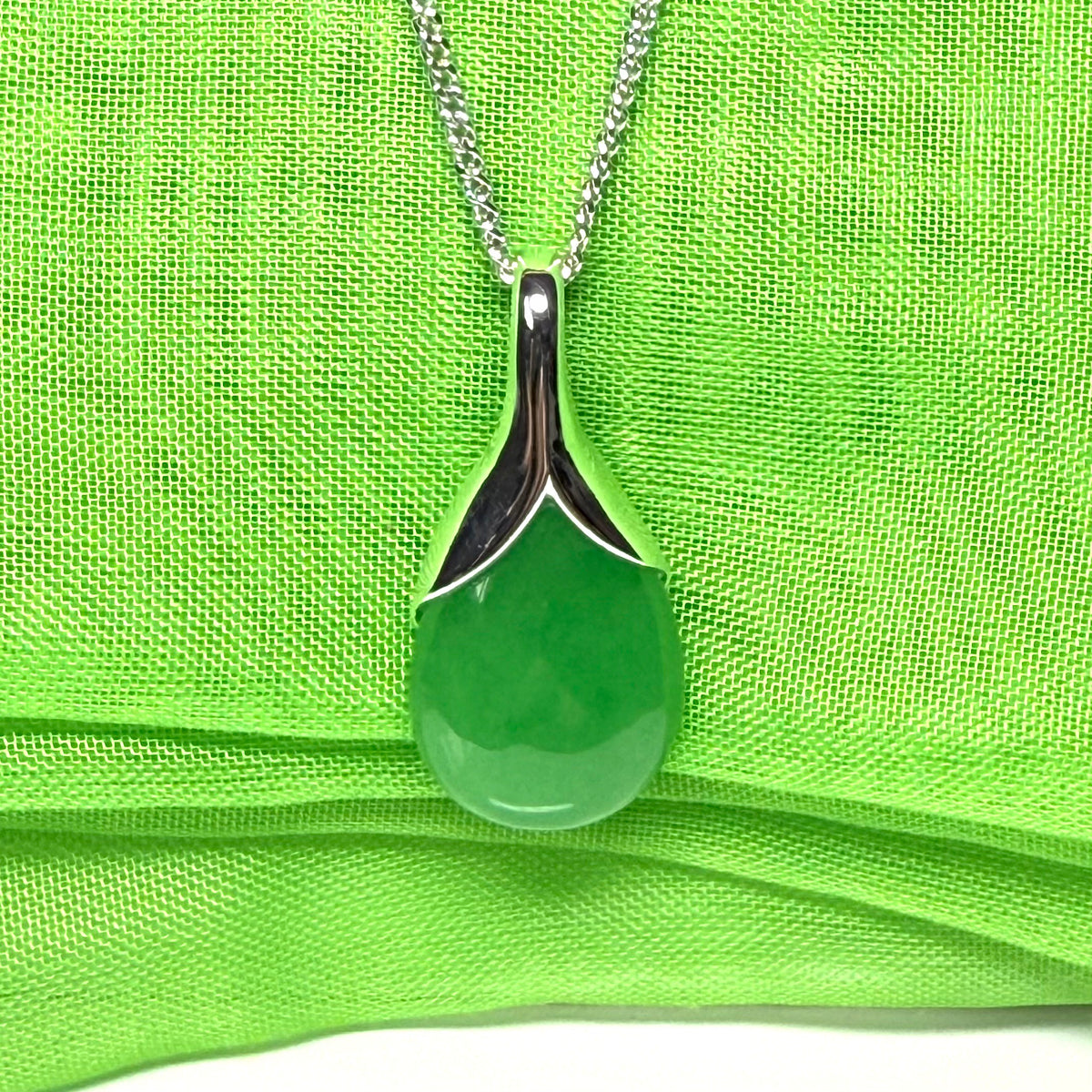 A real green jade pear shaped necklace in a teardrop pendant with a chain included