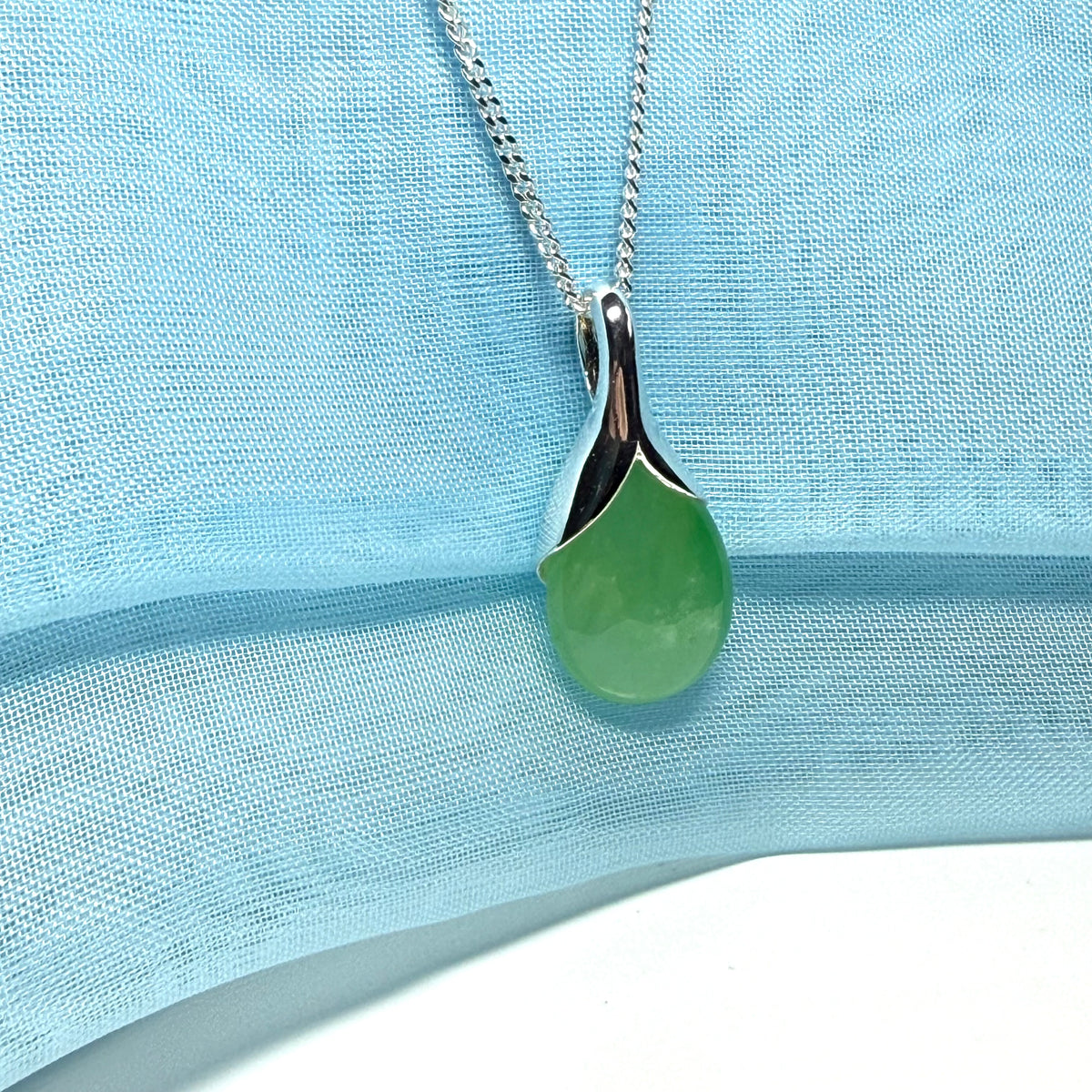 A real green jade pendant necklace in a distinctive teardrop shape or pear shaped designed with a chain