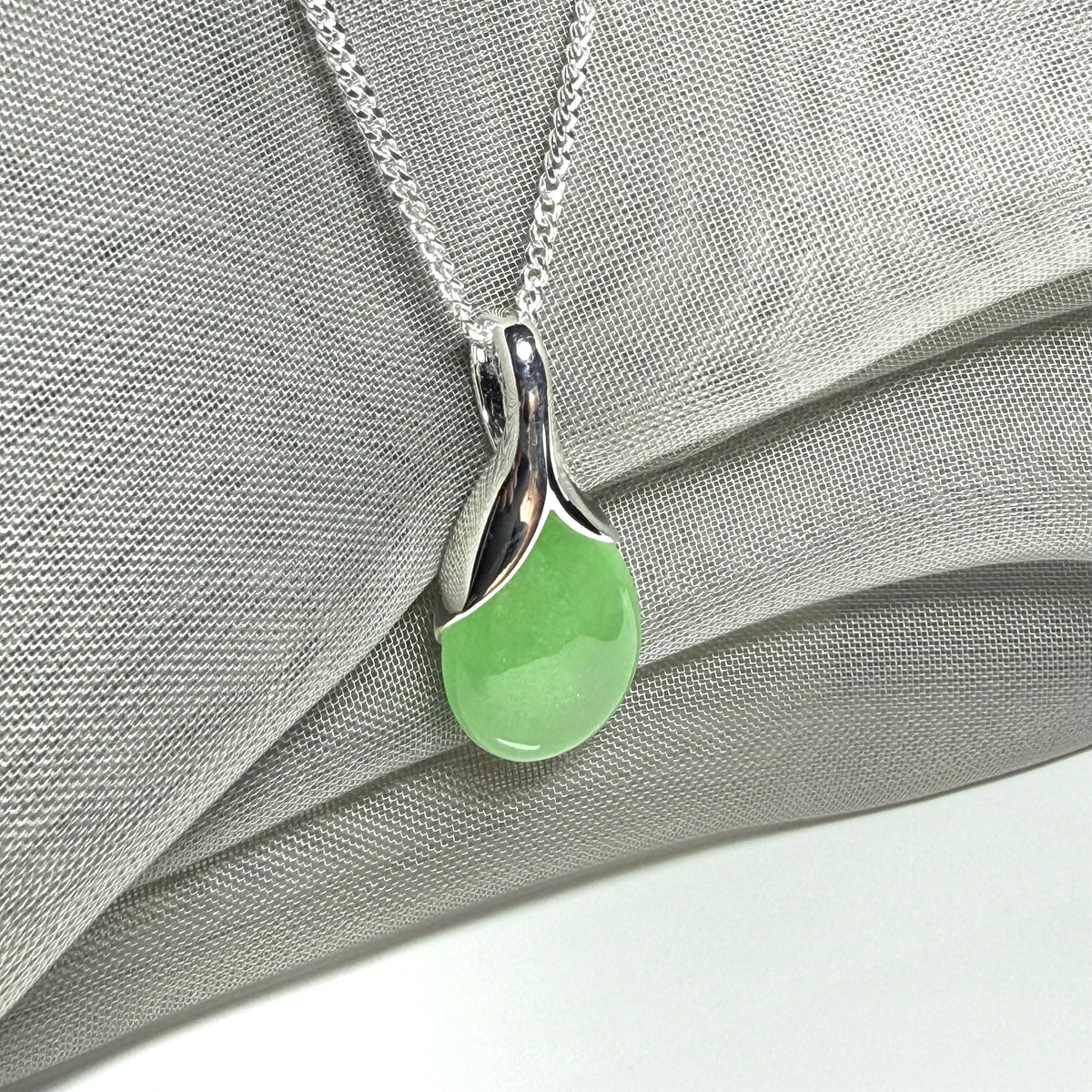 A real green jade pendant necklace in a teardrop shape or pear shaped design