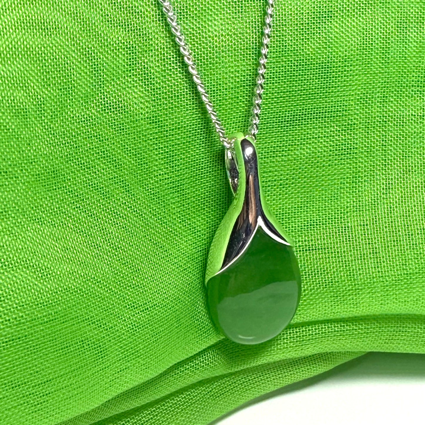 A real green jade pendant necklace in a teardrop shaped or pear shaped