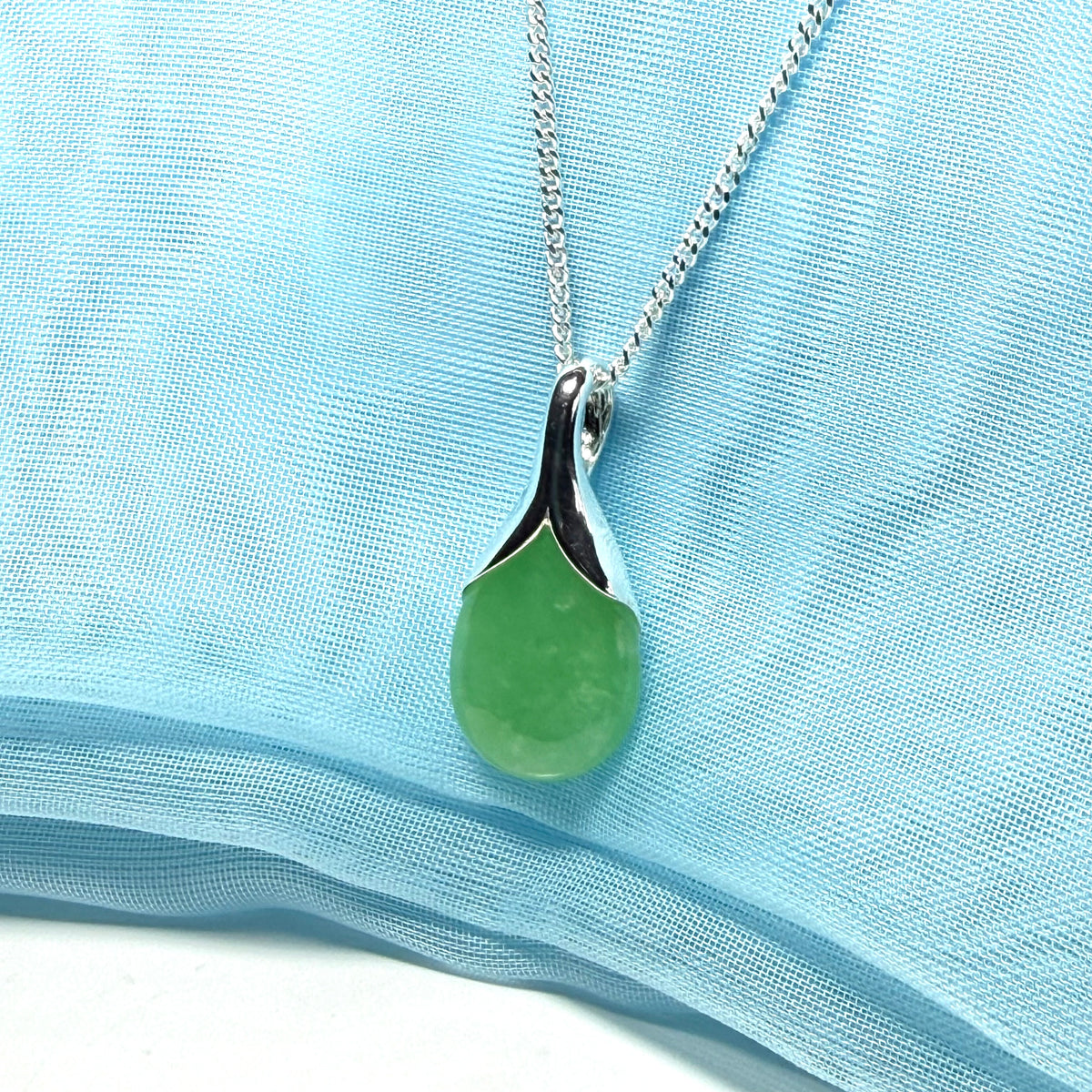 A real jade pendant in a teardrop shape or pear shaped designed green necklace including chain