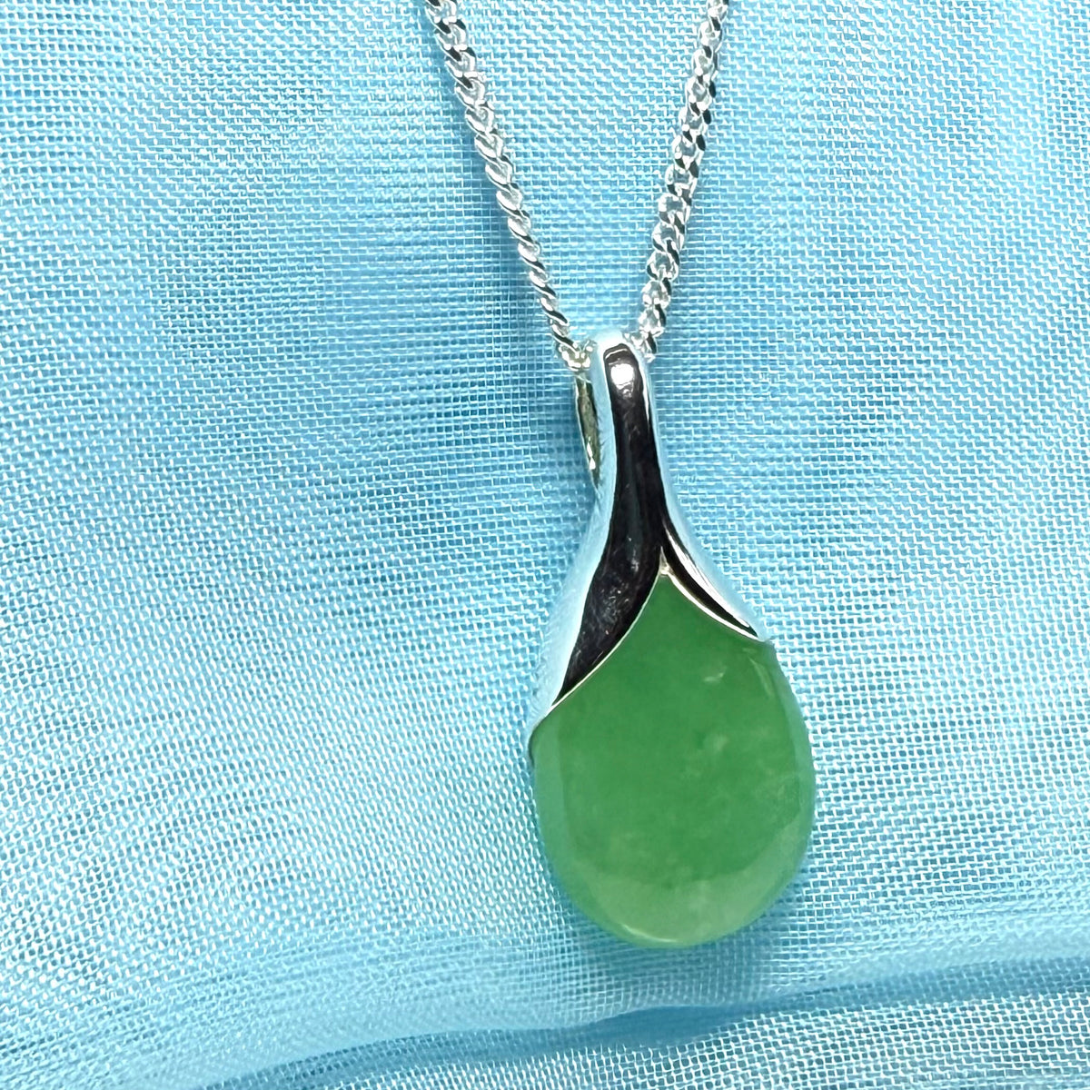 A real jade pendant in a teardrop shape or pear shaped designed green necklace including chain