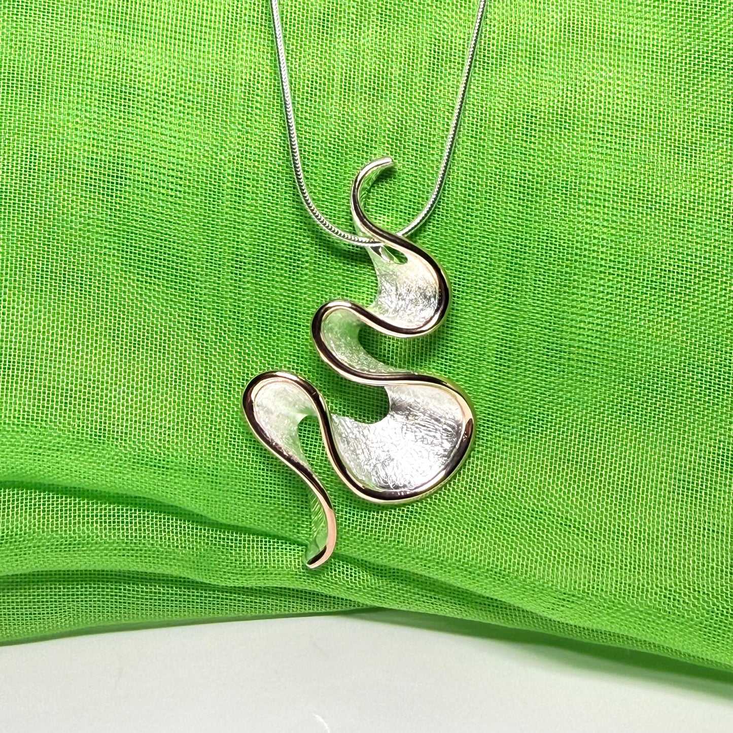 A sterling silver solid rounded open pierced fancy swirl necklace with snake chain