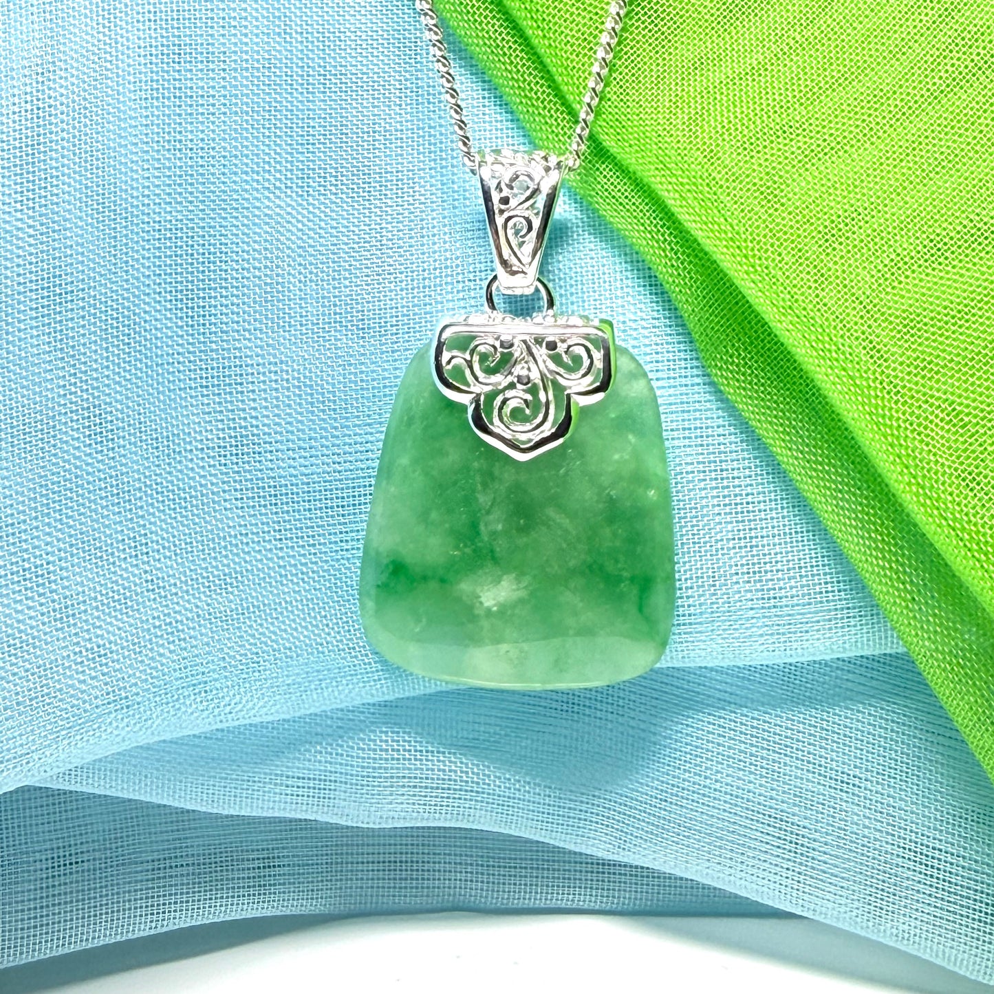 A green real jade necklace with a large shaped and patterned pendant with chain