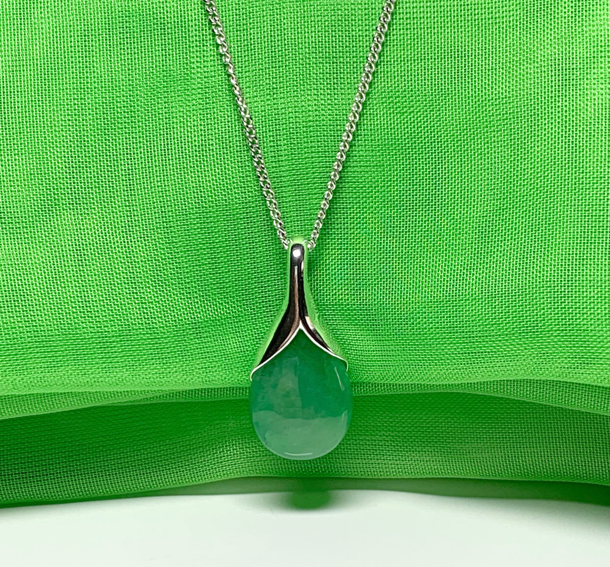 A real green jade pendant necklace in a teardrop shaped or pear shape