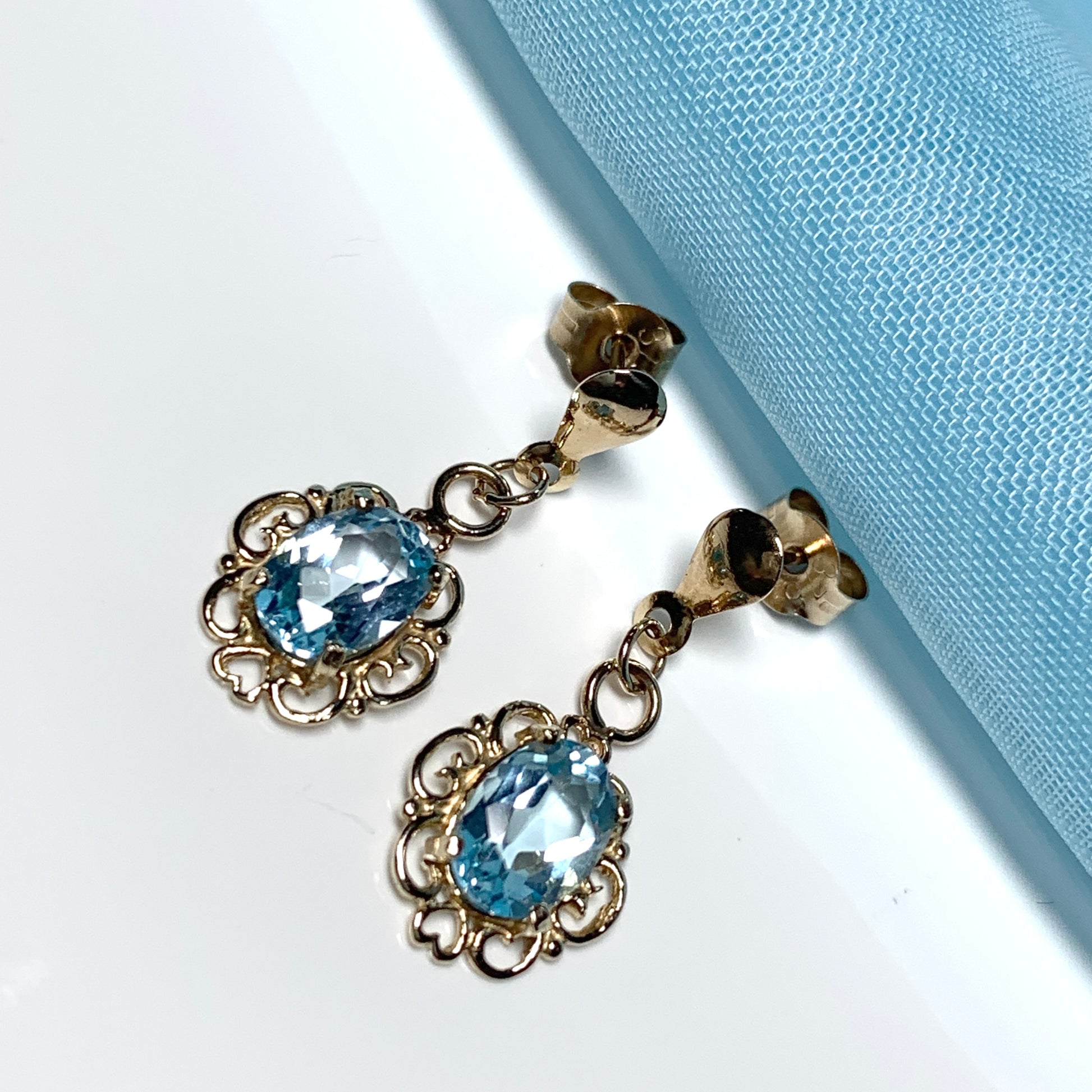 Blue topaz yellow gold oval shaped fancy scrolled drop earrings