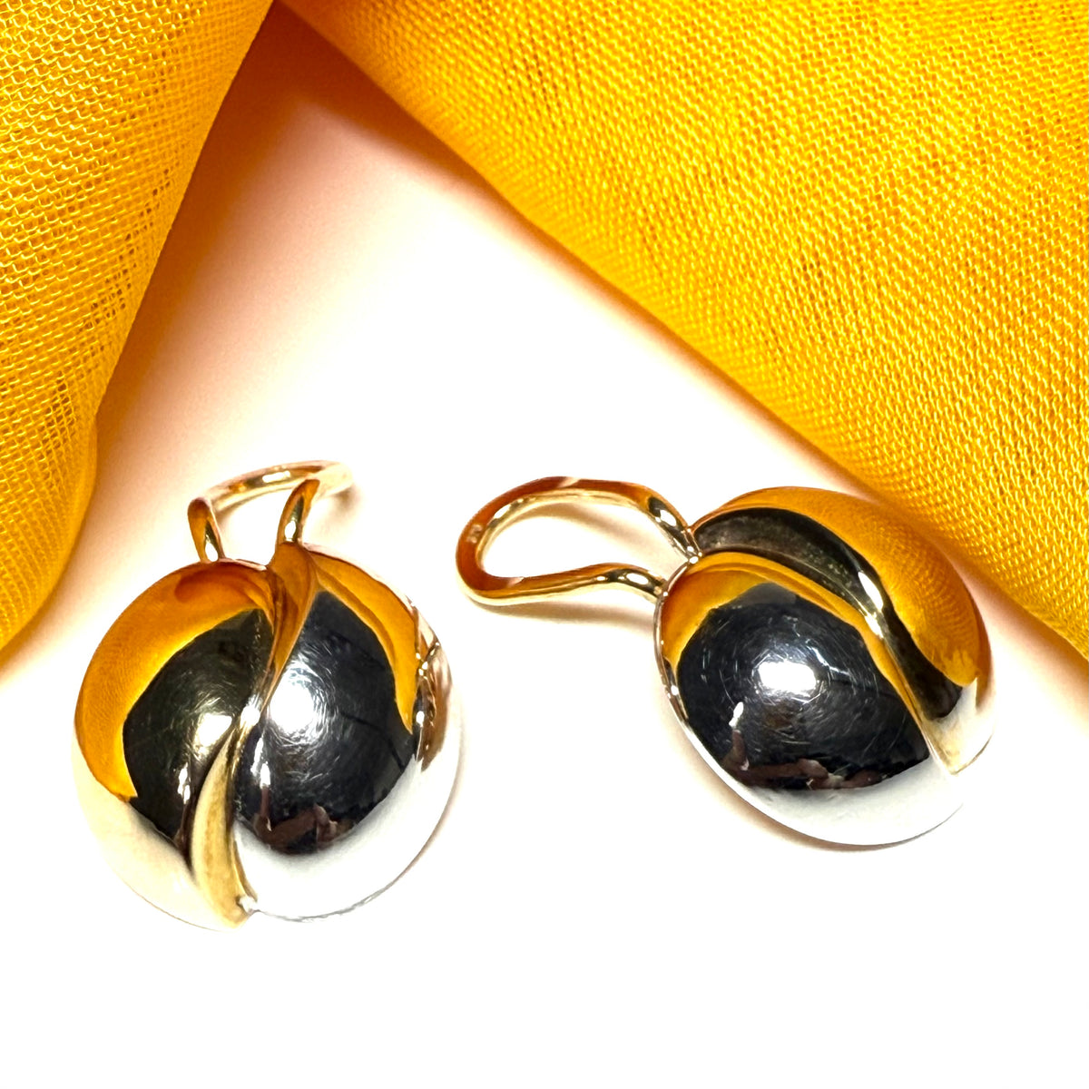 9 carat gold and white gold earrings on a yellow fabric background