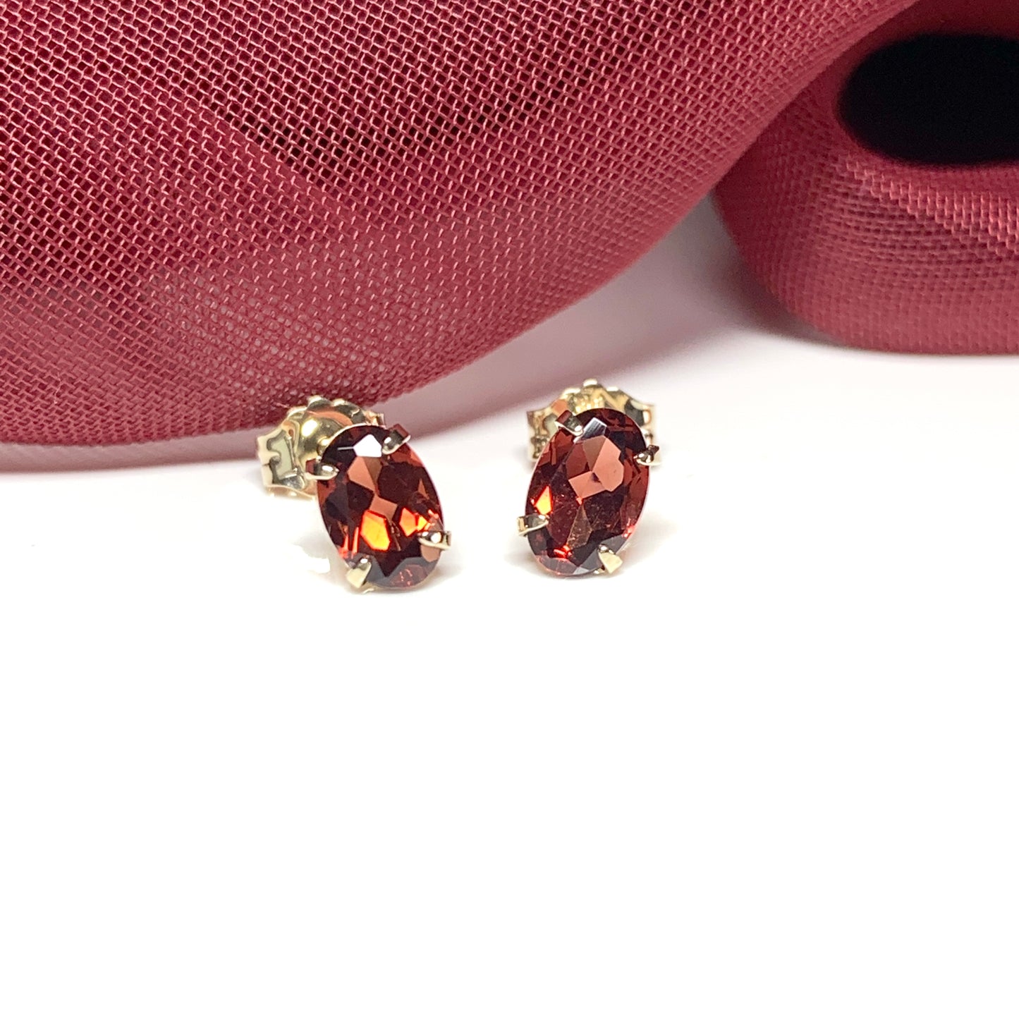 Garnet yellow gold oval four claw stud earrings