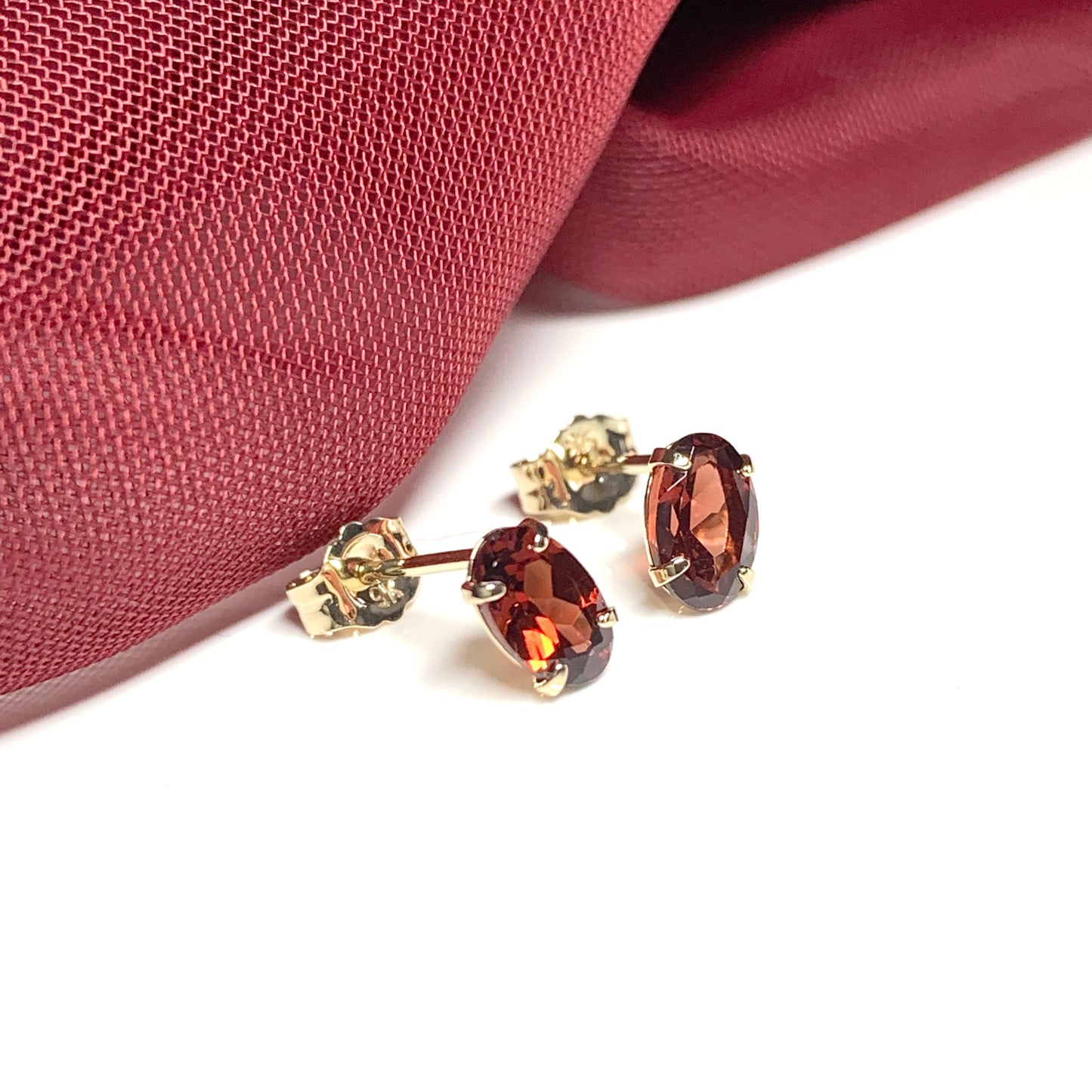 Garnet yellow gold oval four claw stud earrings