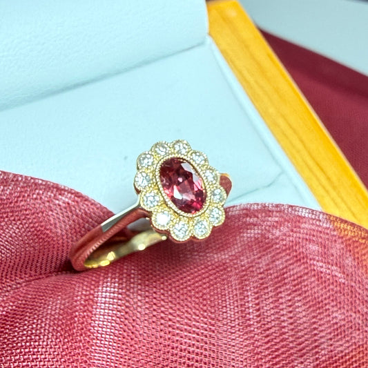 Gold ring with a pink gemstone on a textured fabric background