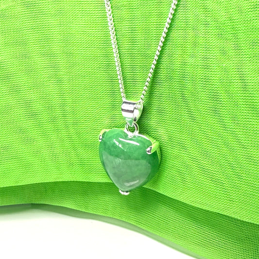 Green heart-shaped pendant on a silver chain against a green fabric background