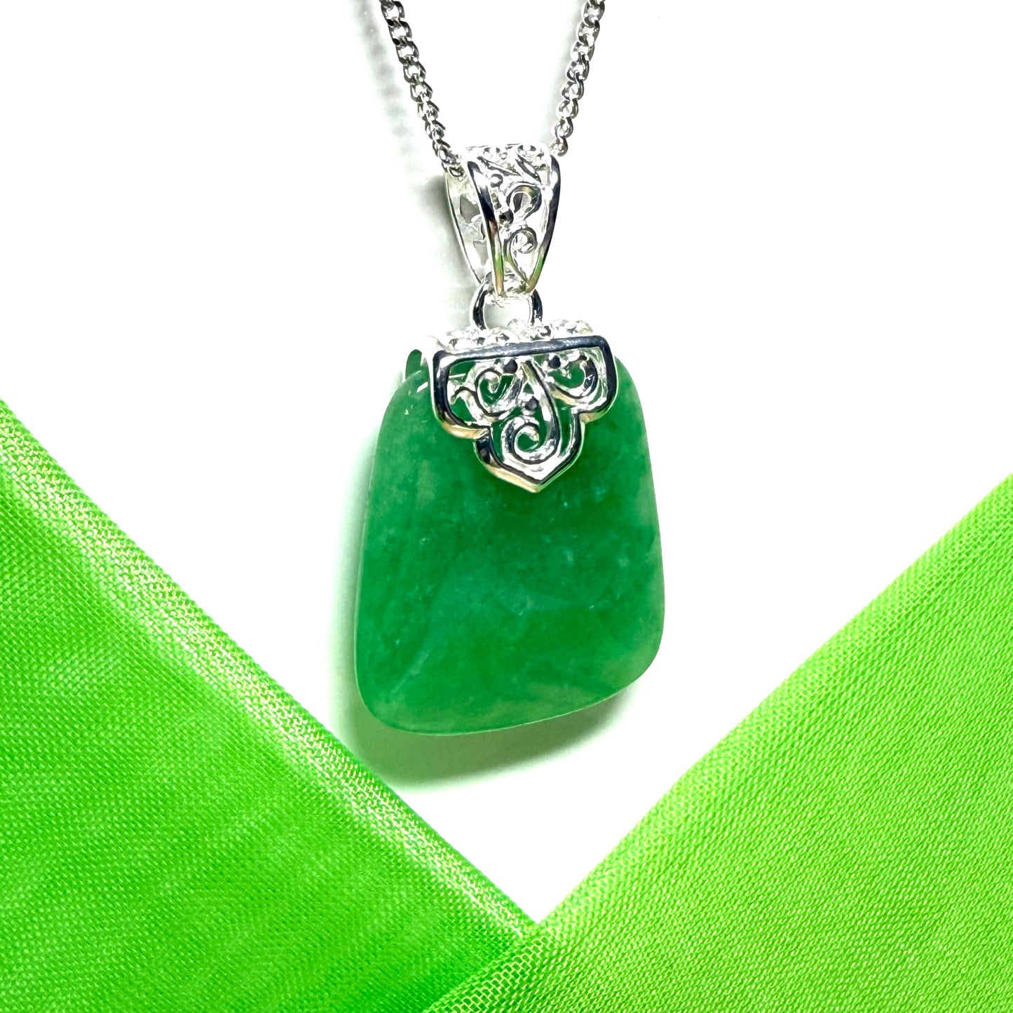 Real green jade stone pendant with silver decorative element on a white background