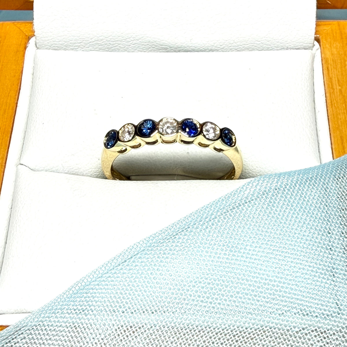 A real blue sapphire and diamond yellow gold eternity ring smooth setting