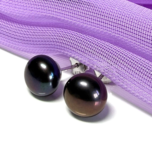 Pair of black pearl earrings on a white background with purple sheer fabric.