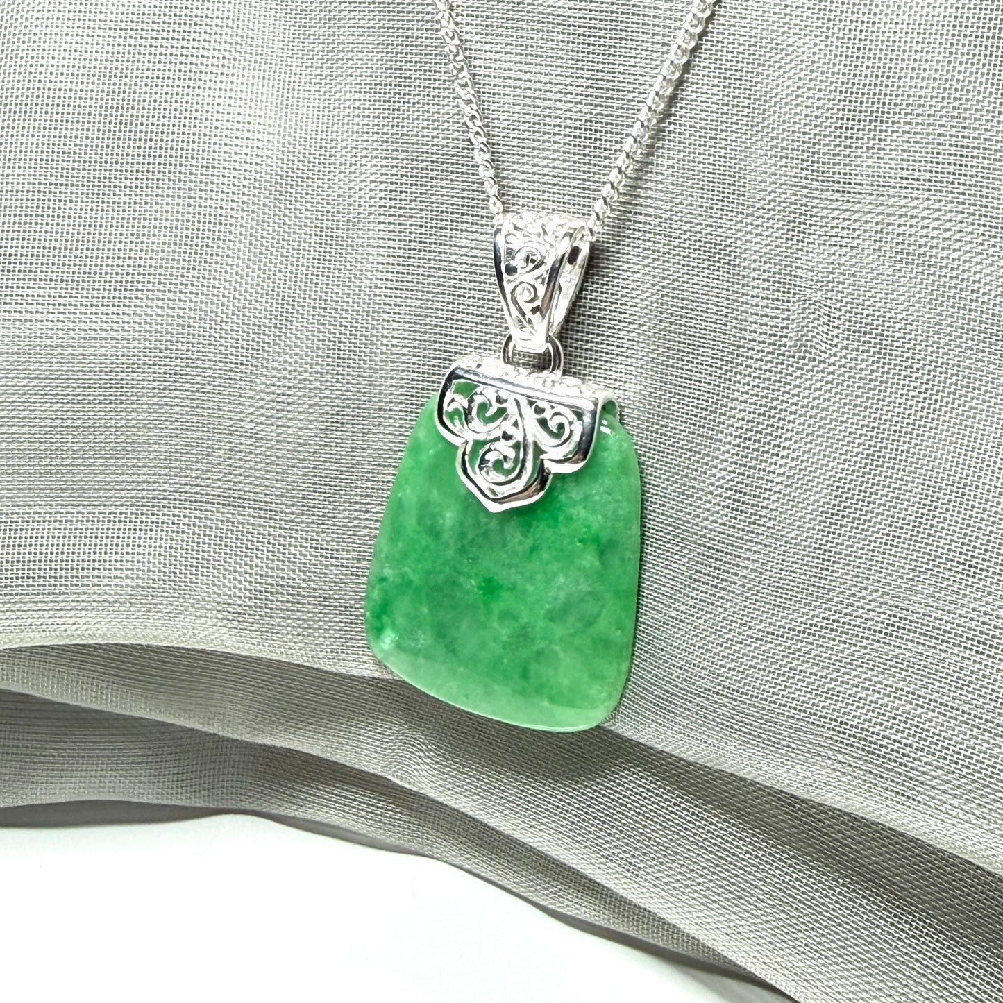 A real green jade necklace large shaped with a patterned top pendant to it with chain