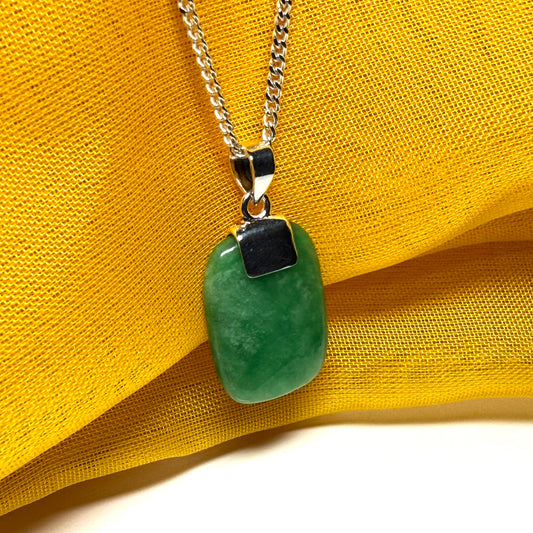 Green pendant necklace on a yellow fabric background