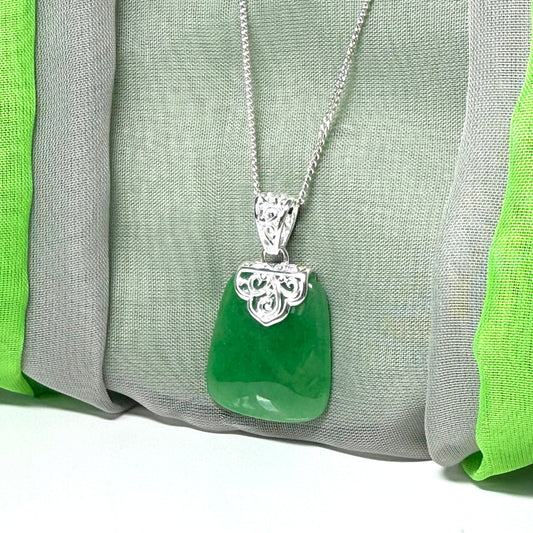 Green pendant necklace with silver chain on a green and gray fabric background