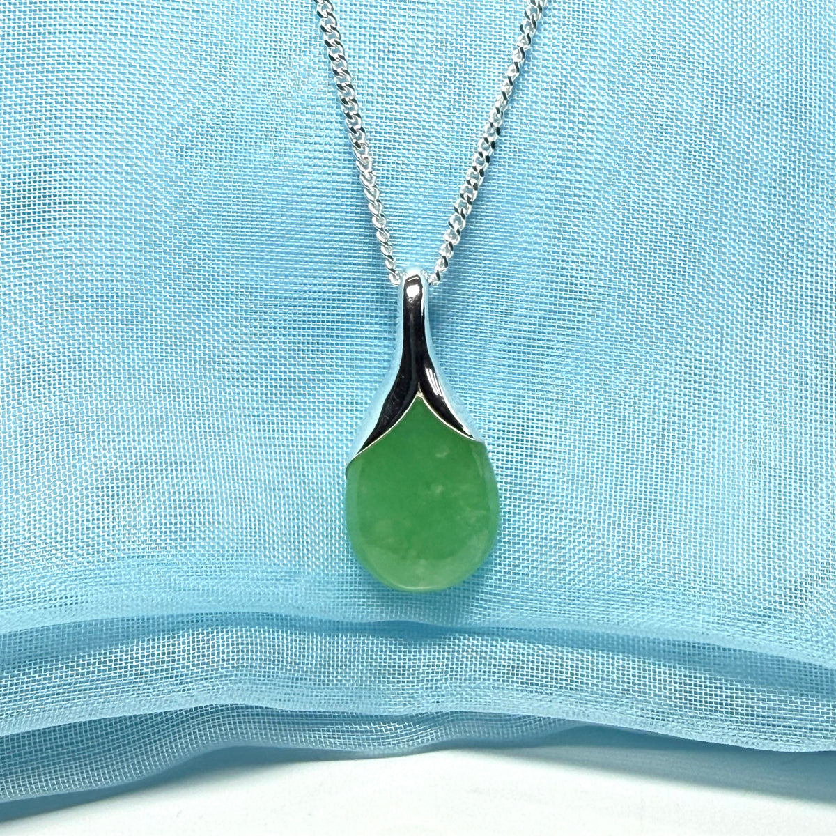 A real jade pendant in a teardrop shape or pear shaped designed green necklace including chain