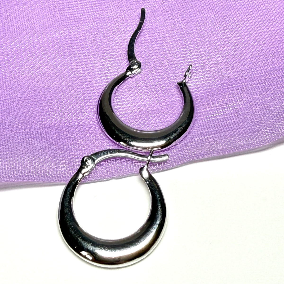Black and silver hoop earrings on a purple surface