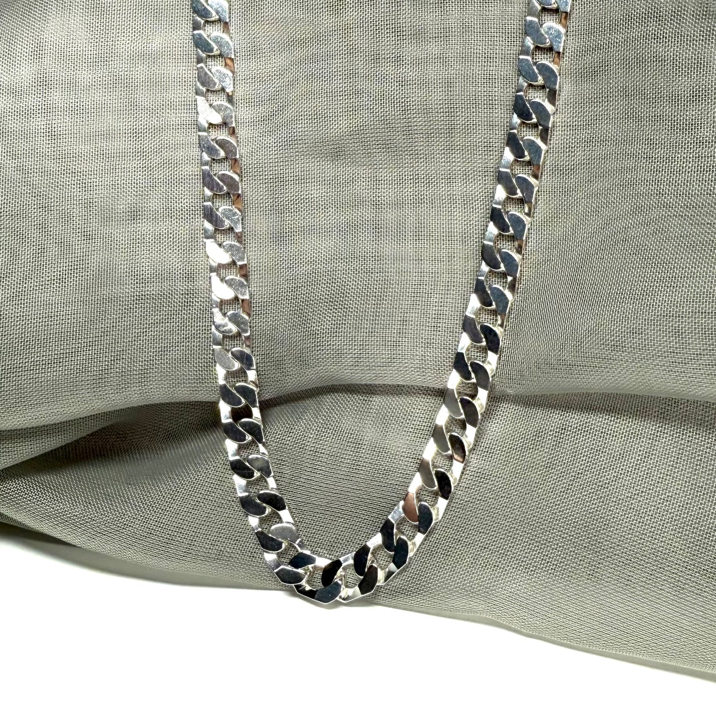 Silver chain necklace on a light gray fabric background