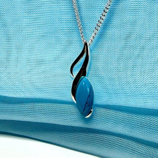 Necklace with a blue pendant on a light blue fabric background