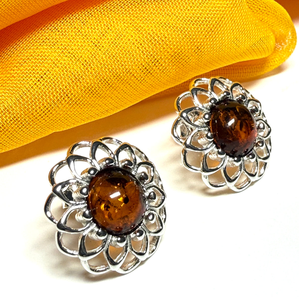 Silver earrings with brown gemstones on a yellow fabric background