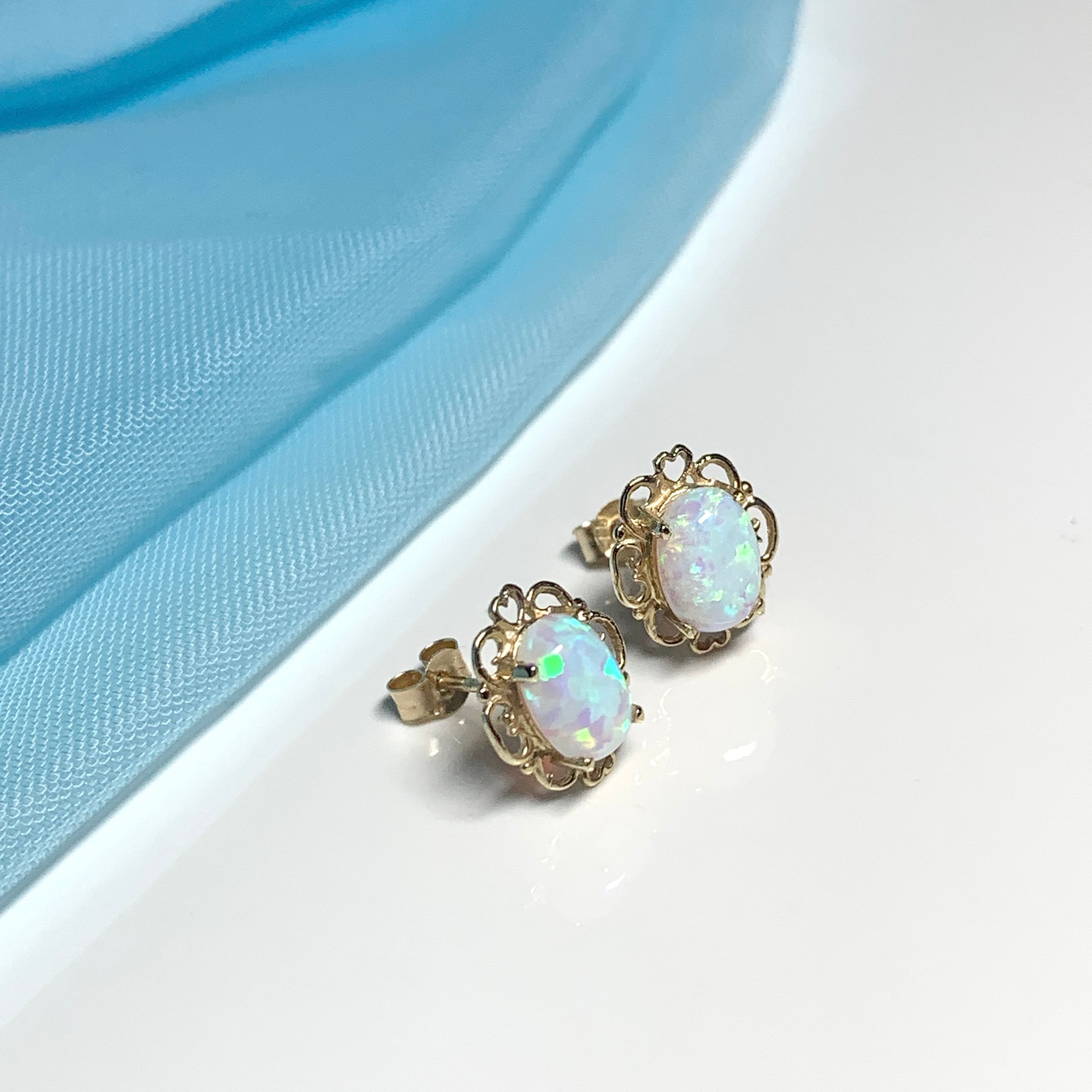 Yellow gold oval opal stud earrings with a pierced setting