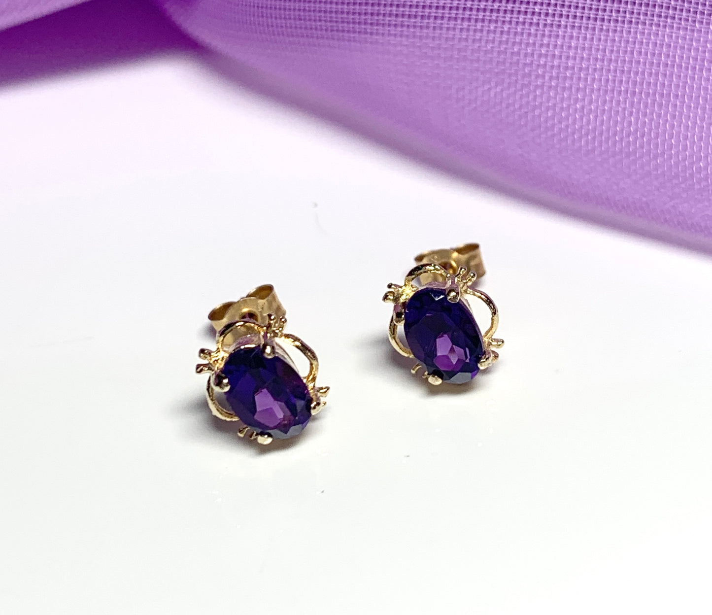 Yellow gold oval purple amethyst stud earrings with fancy edging