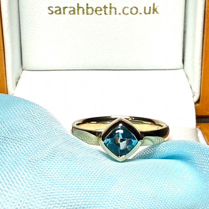 Blue topaz ladies dress ring yellow gold with a smooth rubbed over setting