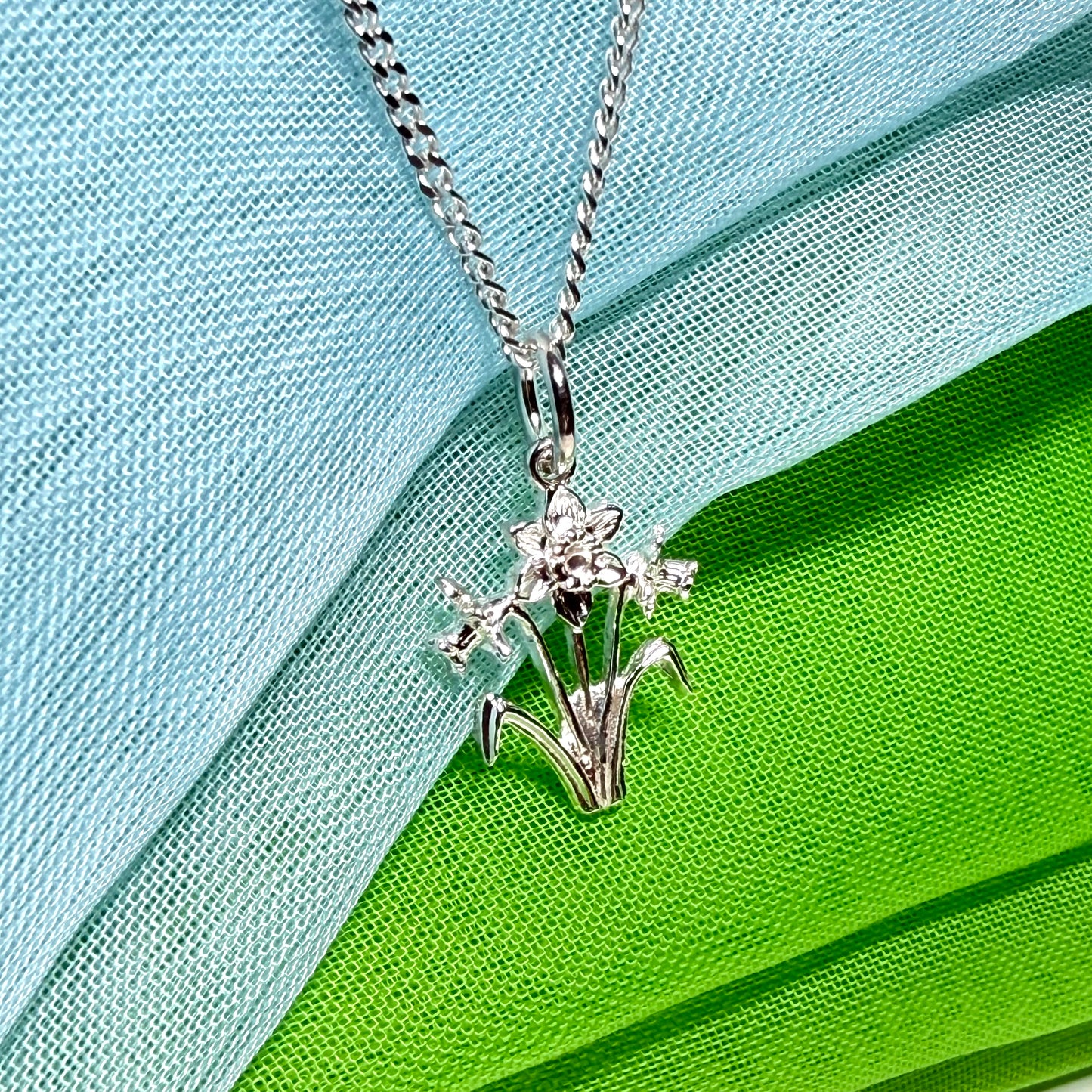 Including chain

Daffodil necklace

Solid

Sterling Silver

Gift box included

This beautiful sterling silver Welsh daffodil flower shaped necklace, that is a perfect addition to a silver jewellery collection.

On a solid sterling silver chain.

Daffodil flowers are often given to a Mum as a sign of love, a perfect Mother’s Day gift idea, or simply for no reason at all.

It is made up of three detailed daffodils on stems, and two leaves one either side.

The daffodil flower is the national flower of Wales