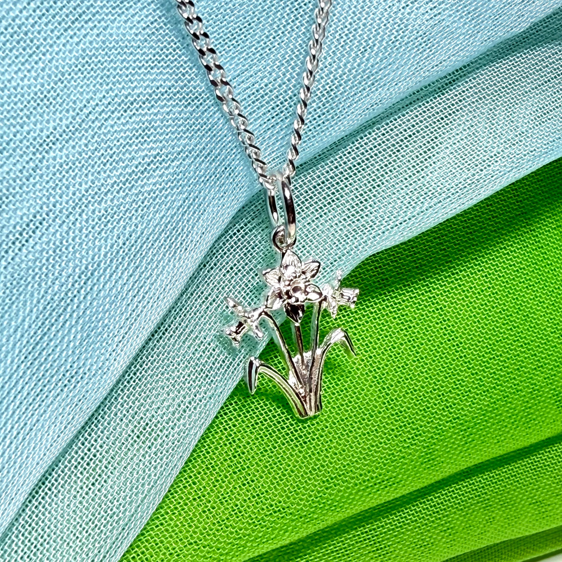 Including chain

Daffodil necklace

Solid

Sterling Silver

Gift box included

This beautiful sterling silver Welsh daffodil flower shaped necklace, that is a perfect addition to a silver jewellery collection.

On a solid sterling silver chain.

Daffodil flowers are often given to a Mum as a sign of love, a perfect Mother’s Day gift idea, or simply for no reason at all.

It is made up of three detailed daffodils on stems, and two leaves one either side.

The daffodil flower is the national flower of Wales
