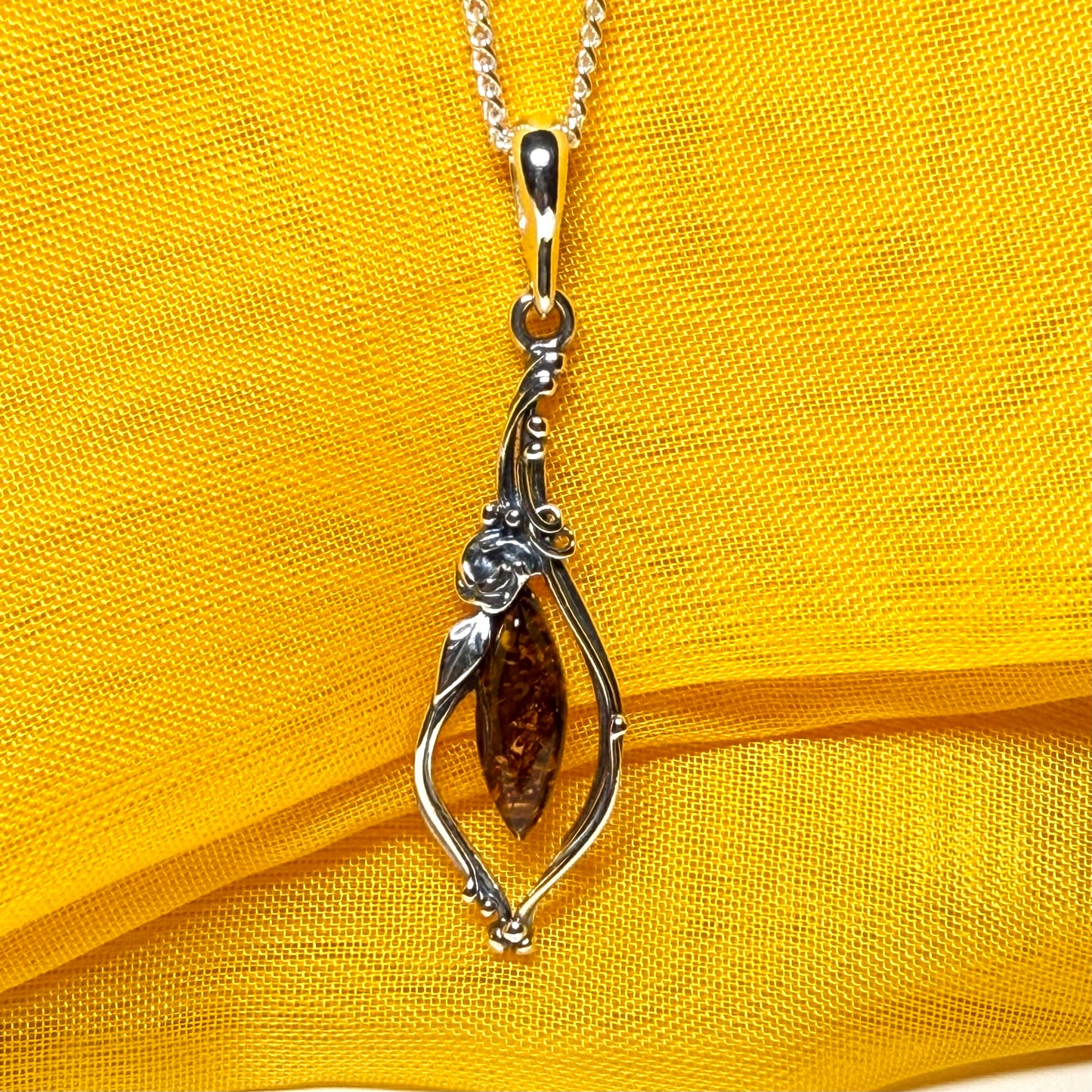 Real amber oval sterling silver necklace with a swirl set fancy patterned open pendant