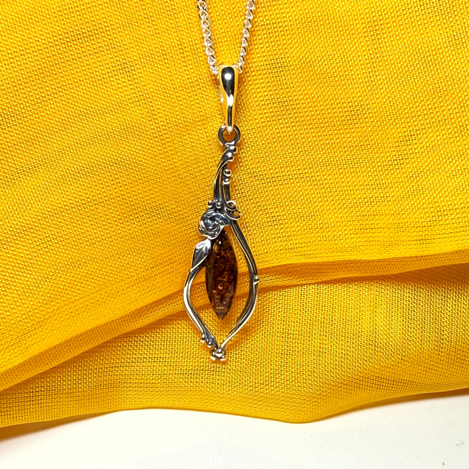 Real amber oval sterling silver necklace with a swirl set fancy patterned open pendant